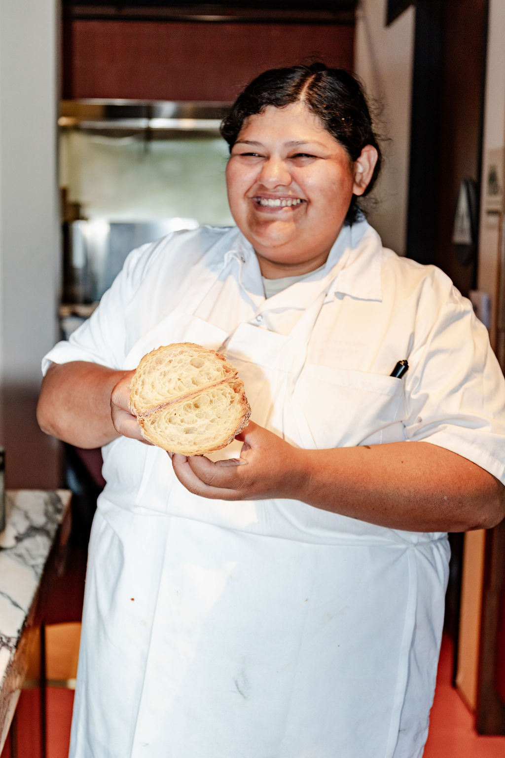 Ellen Ramos holding a split laminated pastry in the kitchen